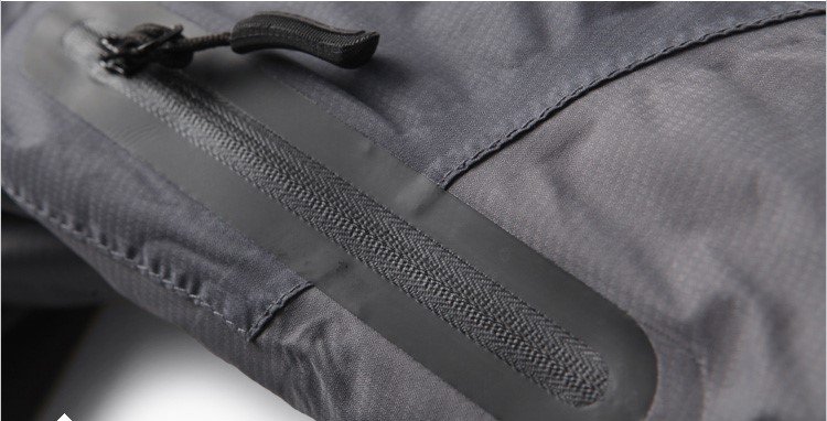 Close - up of a black waterproof zipper attached to a grey fabric, likely on a bag or garment