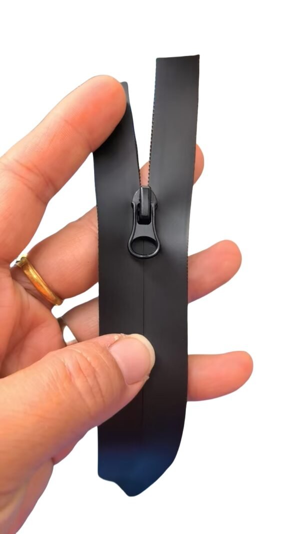 Close - up of a black zipper held by a hand with a ring