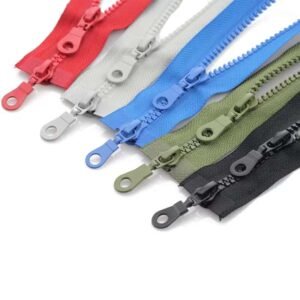 A collection of zippers in vibrant colors including red, light gray, blue, olive green, and black, each with distinct slider designs.
