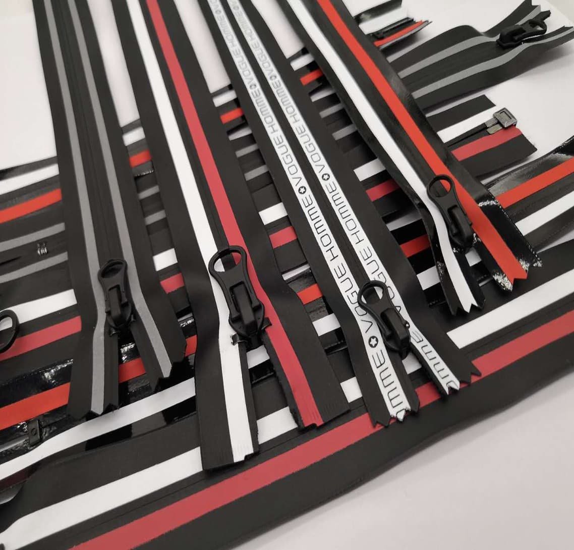 A display of zippers with black, white, and red stripes, some with text on them