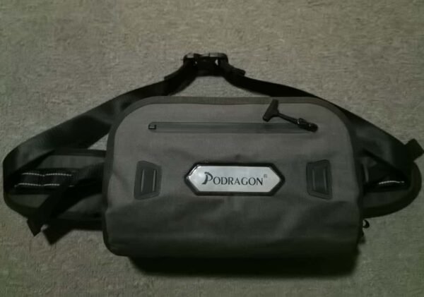 Gray PODRAGON waist bag with a front zipper pocket and black strap, displayed on a textured surface.