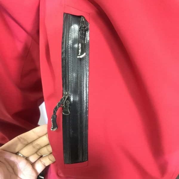 Black waterproof zipper installed on red outdoor jacket pocket, heavy‑duty sealed zipper for hiking wear